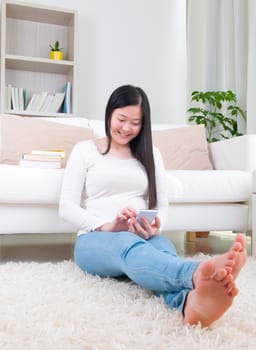 Smartphone mobile apps concept. Chinese girl using smart phone. Asian girl relaxed and lying on the living room.