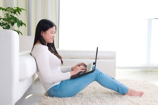 Portrait of attractive Asian girl using laptop. Young woman indoors living lifestyle at home.