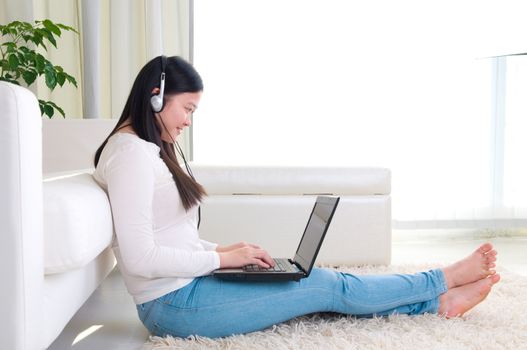 Portrait of attractive Asian girl using laptop. Young woman indoors living lifestyle at home.