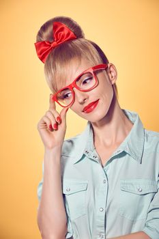 Beauty fashion portrait business woman in stylish red glasses thinking, idea. Attractive pretty blonde girl smiling. Confidence, Pinup hairstyle bow makeup.Unusual playful, emotions.Vintage, on yellow