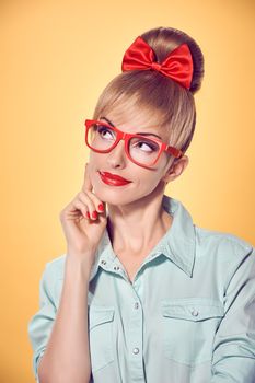 Beauty fashion portrait business woman in stylish red glasses thinking, idea. Attractive pretty blonde girl smiling. Confidence, Pinup hairstyle bow makeup.Unusual playful, emotions.Vintage, on yellow