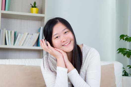 Portrait of Asian girl hand holding face, relaxed and smiling at home, adult girl living lifestyle indoors.