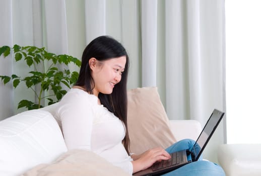 Portrait of attractive Asian girl using laptop. Young woman indoors living lifestyle at home.