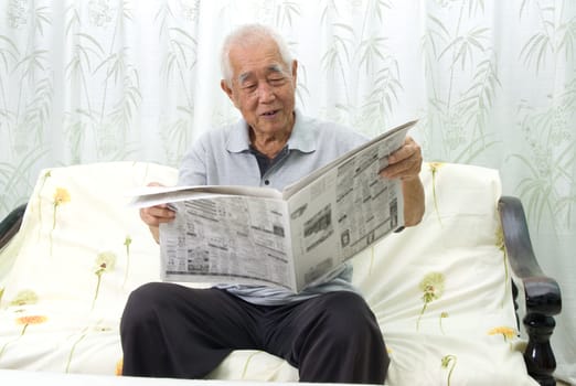  Portrait of chinese senior man reading newspaper at home. 