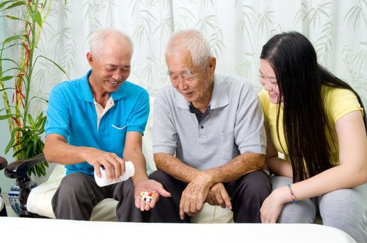Asian senior man having medicine at home. Adult son and grandchild caring for a senior man.