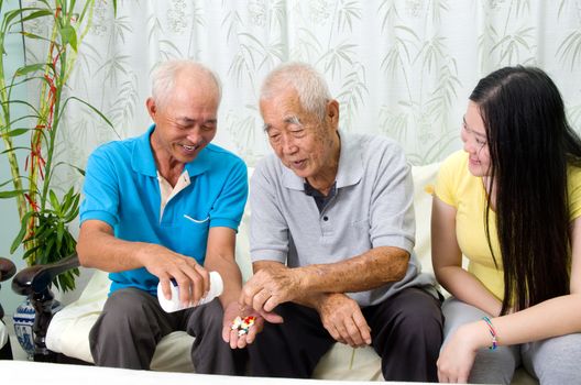 Asian senior man having medicine at home. Adult son and grandchild caring for a senior man.