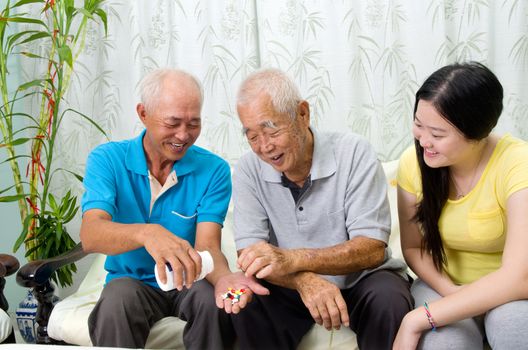 Asian senior man having medicine at home. Adult son and grandchild caring for a senior man.
