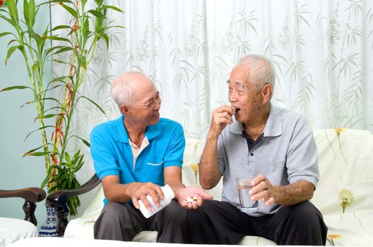 Asian senior man having medicine at home. Adult son caring for a senior man.