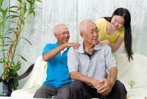 Asian old man shoulder pain, sitting on sofa , grandchild and son massaging their father and grandfather shoulder. Chinese family, senior retiree indoors living lifestyle at home.