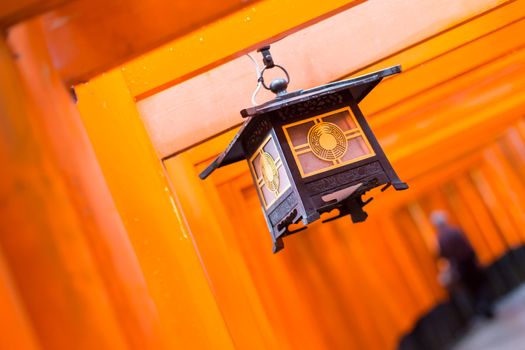 Red Tori Gate at Fushimi Inari Shrine in Kyoto, Japan. Selective focus on traditional japanese lamp.