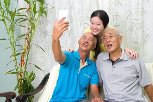 Modern technology, age and people concept. Asian family using smart-phone, self photographing. Family living lifestyle at home.