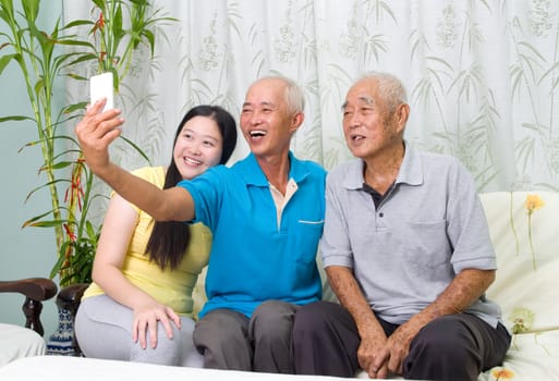 Modern technology, age and people concept. Asian family using smart-phone, self photographing. Family living lifestyle at home.