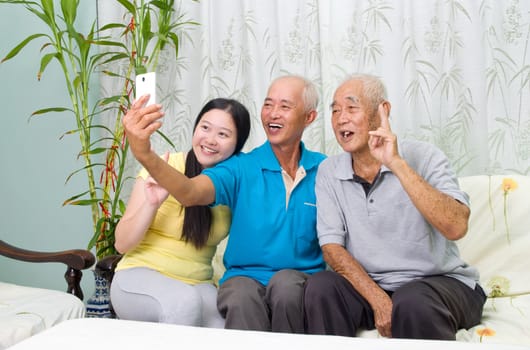 Modern technology, age and people concept. Asian family using smart-phone, self photographing. Family living lifestyle at home.