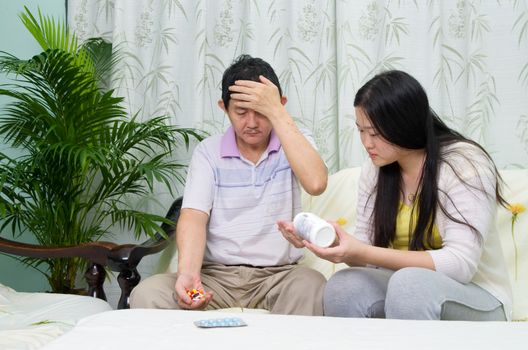 Asian man having medicine at home. Daughter take care of her father. 