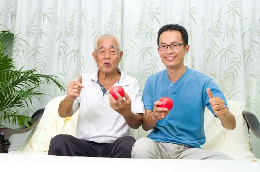 Asian senior man and son making okay sign while holding an apple