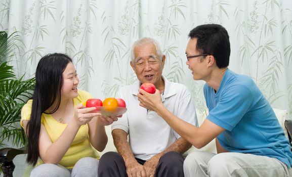 Happy asian family eating healthy fruit.