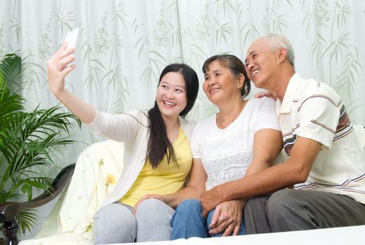 Modern technology, age and people concept. Asian girl with his parent taking selfie, using smartphone, self photographing.