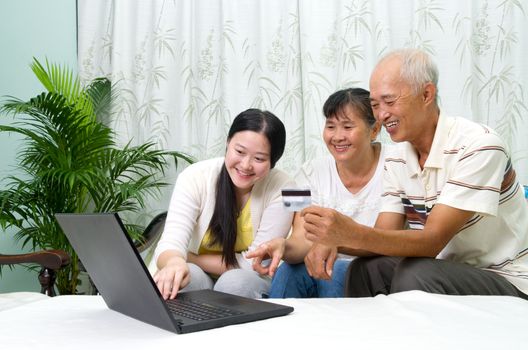 Asian parent learns to use tablet computer with their daughter