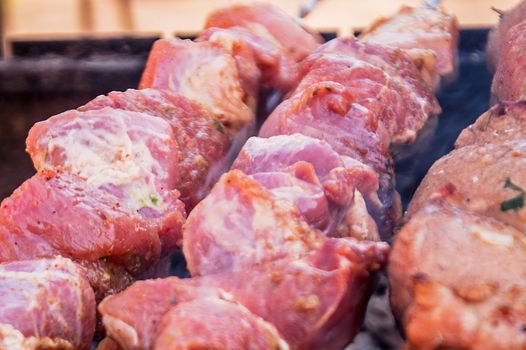 preparation of pieces of crude, marinated meat on a grill 