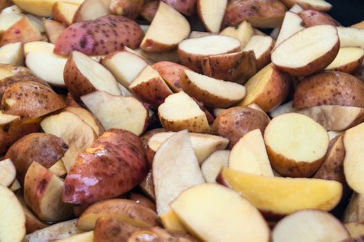 potatoes cut by pieces in a peel before frying on a plate
