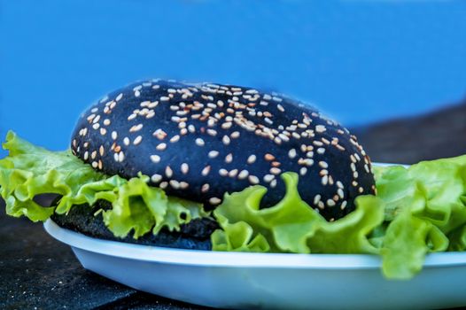 the lying tasty black burger with salad and sesame   