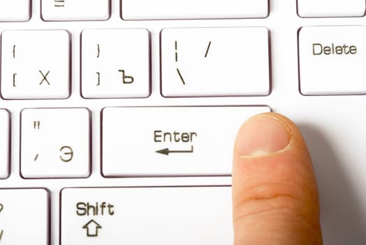 Closeup view of white keyboard with human finger