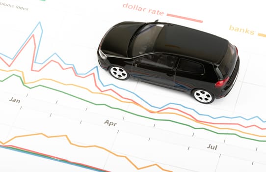 Black car on graphical charts background, closeup
