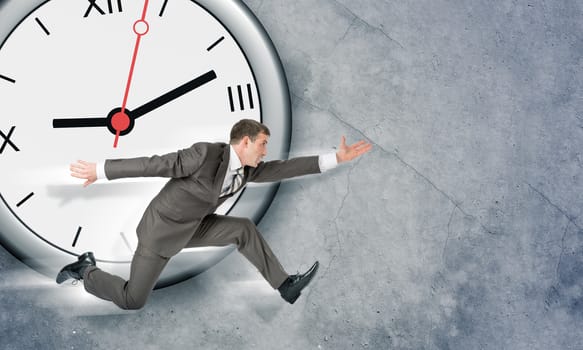 Businessman running with big clock on grey background