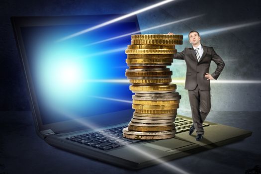 Businessman with big stack of coins standing on laptop