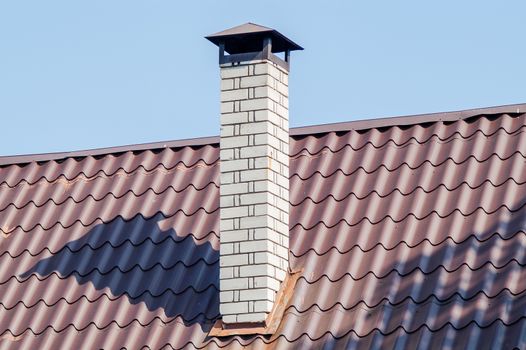 white brick chimney on the roof with blue sky