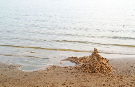 Heap of clean sand shaped as a castle on sea beach