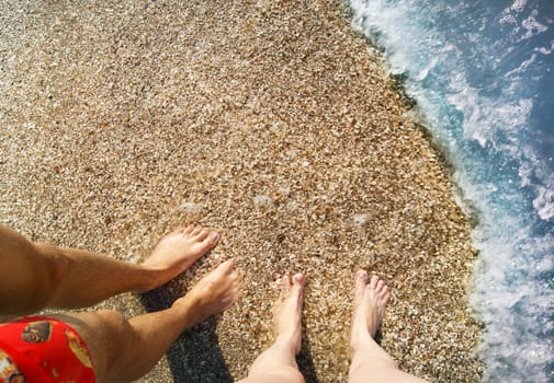 View on shoeless feet of a man and a girl in the water