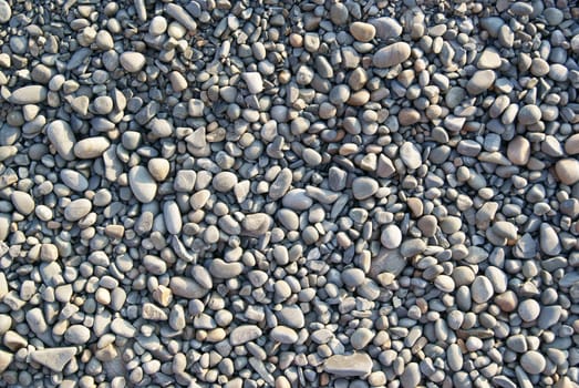 Background of light gray gravel waterworn pebbles on sea beach