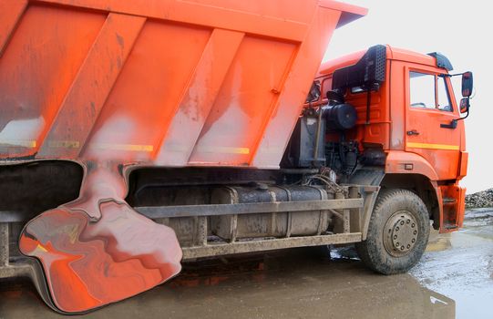 Orange dump truck eroded by caustic substance 