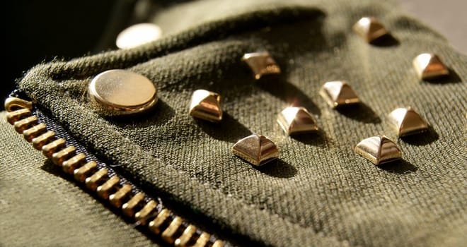 Closeup of girl's jacket with golden metal spikes, swag style