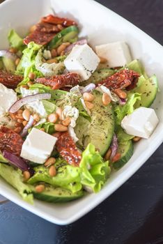 Salad feta cheese lettuce sausage cucumbers and pine nuts