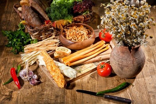 Cheese, camomiles and vegetables on an old wooden table