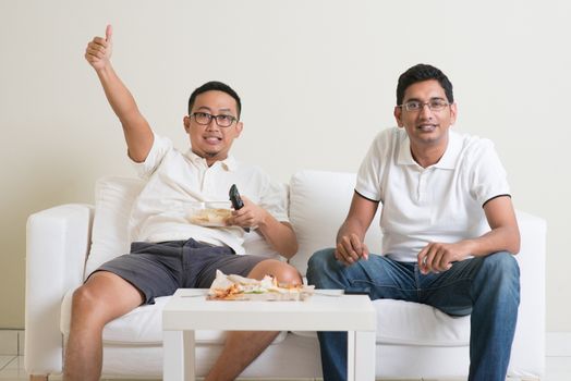 Friendship, sports and entertainment concept. Happy male friends watching sports together on tv at home.