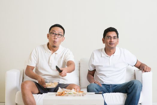 Men sitting on couch watching television, Asian people friendship at home.