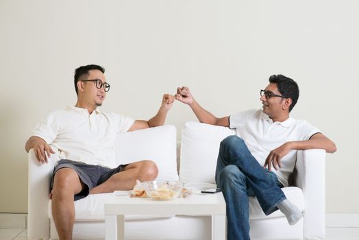 Friends sitting on sofa and giving hand promise at home. Multiracial people friendship.