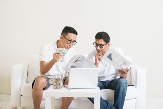eBusiness concept. Asian men working from home. Young guys counting cash with partner, earning money from their successful online business. 