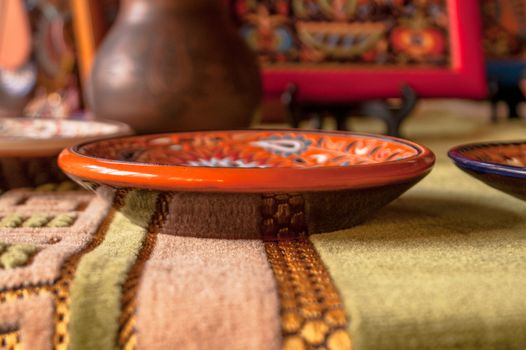 beautiful painted earthenware dish on the background of a jug