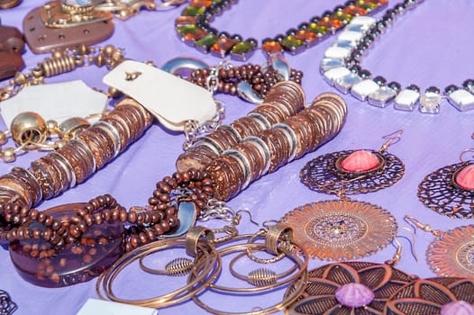 Different bright, multi-colored jewelry of handwork in a sunlight