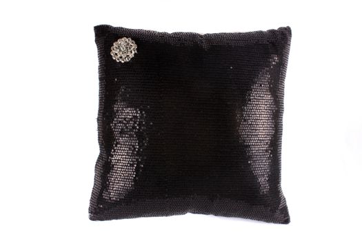 A luxurious pillow made with a design of black sequins and a brooch.