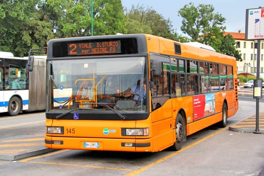 VENICE, ITALY - JULY 30, 2014: Orange city bus Iveco CityClass at the city street.