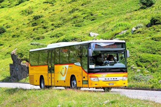 GOTTHARD PASS, SWITZERLAND - AUGUST 5, 2014: Yellow suburban coach Setra S415H at the high mountain Alpine road.