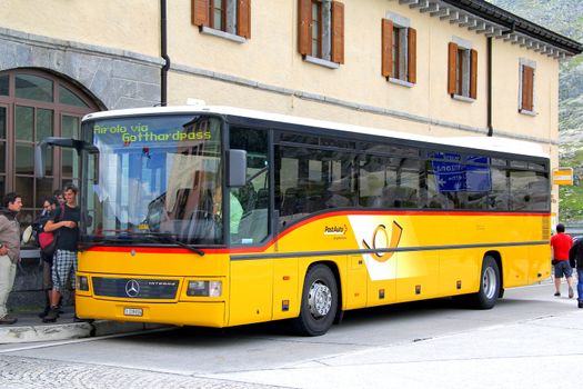 GOTTHARD PASS, SWITZERLAND - AUGUST 5, 2014: Yellow suburban coach Mercedes-Benz O550 Integro at the high mountain Alpine road.