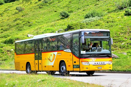 GOTTHARD PASS, SWITZERLAND - AUGUST 5, 2014: Yellow suburban coach Setra S415H at the high mountain Alpine road.