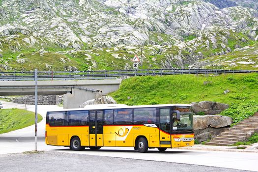 GOTTHARD PASS, SWITZERLAND - AUGUST 5, 2014: Yellow suburban coach Setra S415H at the high mountain Alpine road.