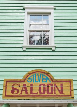 Detail of the facade of a saloon painted green with white windows.